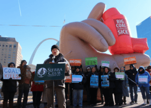 A photo of a rally with a Sierra Club poster at the speaker podium